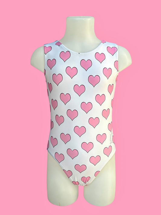 High-quality girls’ pink gymnastics leotard with heart print, sleeveless design, and professional stitching, ideal for toddlers and kids’ dance or gym practice in the UK. ‘R’ logo in small diamantés on left hip.